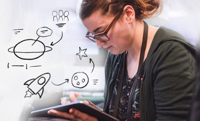 Katrin Mäntele zeichnet am iPad, davor eine Zeichnung mit Weltraumsymbolen